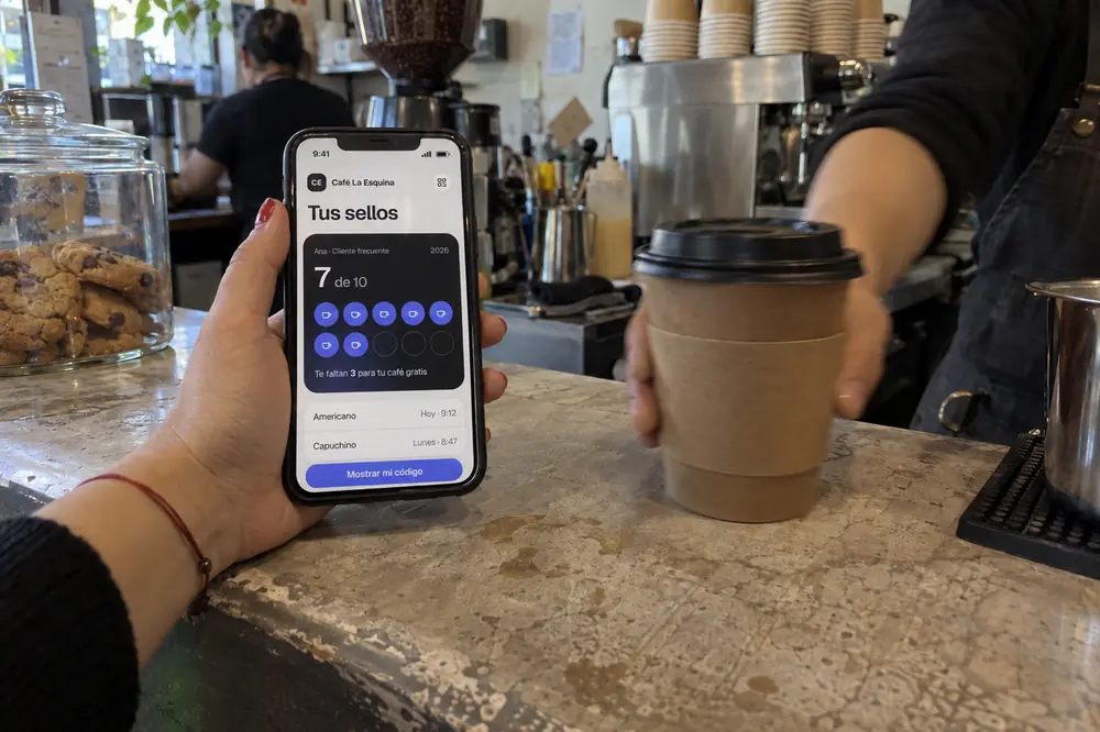 Ejemplo: una clienta enseña su tarjeta de sellos en el celular mientras le entregan su café
